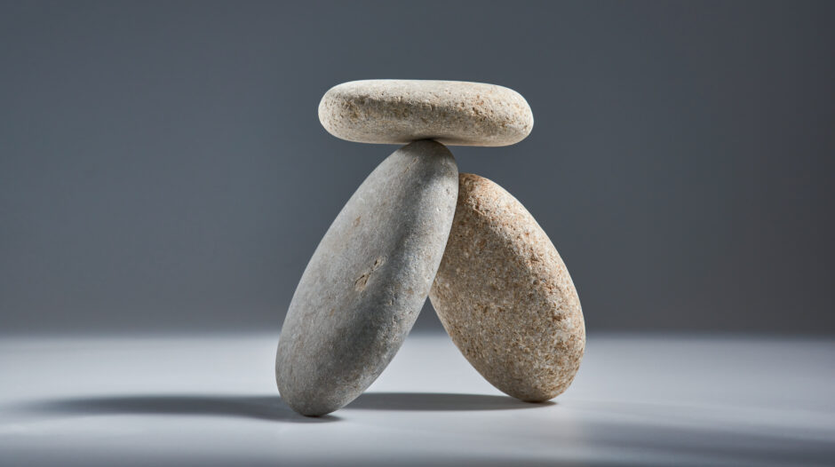 Balancing pyramid of sea pebbles on a gray background, the concept of harmony and balance, heavy and light. Stones in the form of scales with balancing stones.