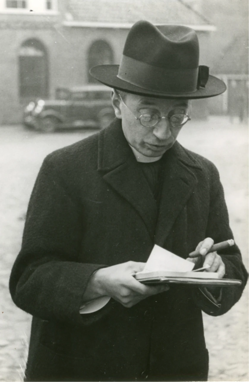 Titus Brandsma met een sigaar en boeken in zijn hand