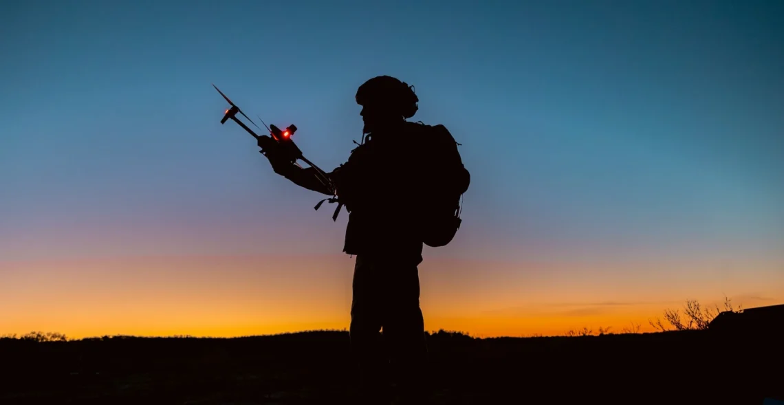 Soldaat staat in de schemer en houdt een drone vast