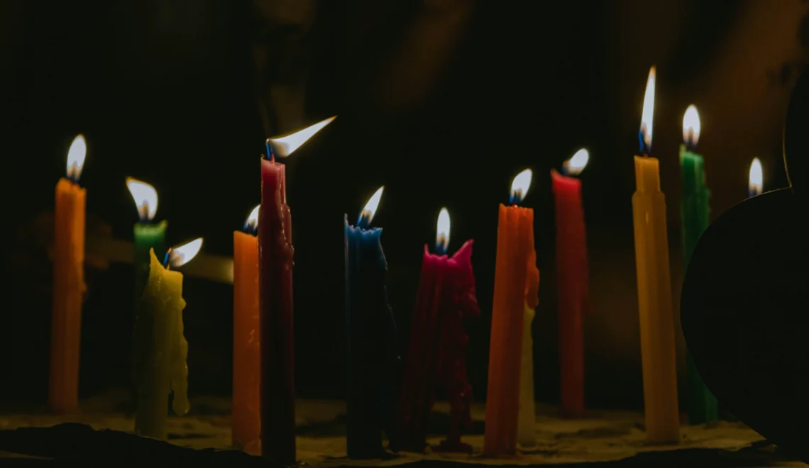 Rij aangestoken kaarsen met verschillende lengtes en verschillende kleuren met een donkere achtergrond