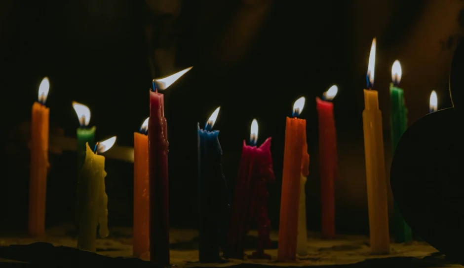 Rij aangestoken kaarsen met verschillende lengtes en verschillende kleuren met een donkere achtergrond